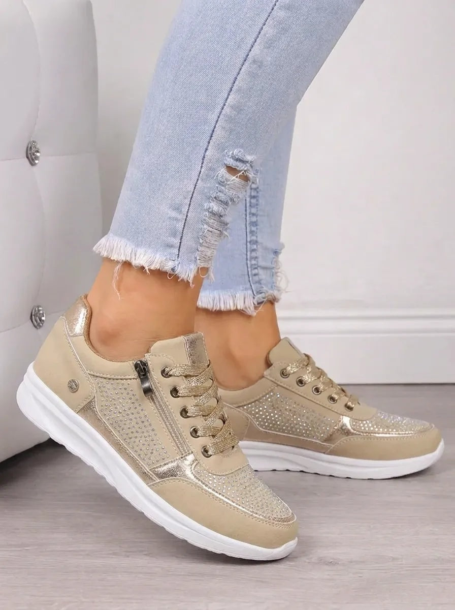 Beige-gold low-top sneakers with lace-up fronts, side zips, sparkling panels, and contrasting white soles.
