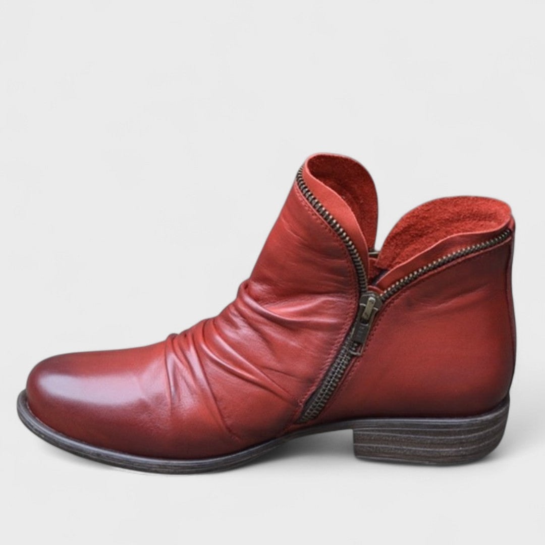 Red ankle boot shown side-on, featuring a diagonal side zip and a short stacked heel.