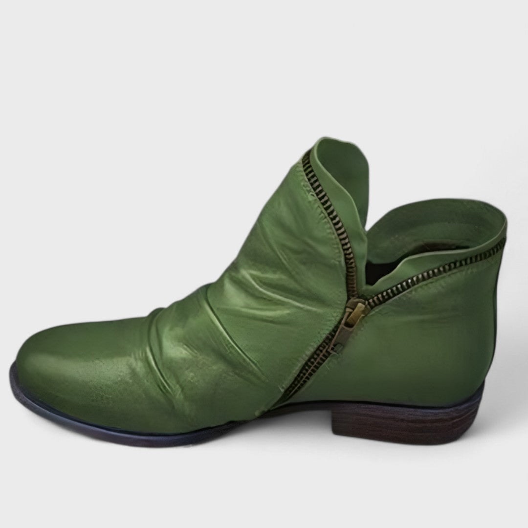 Green ankle boot viewed from the side, showing its diagonal zip and contrasting dark low heel.