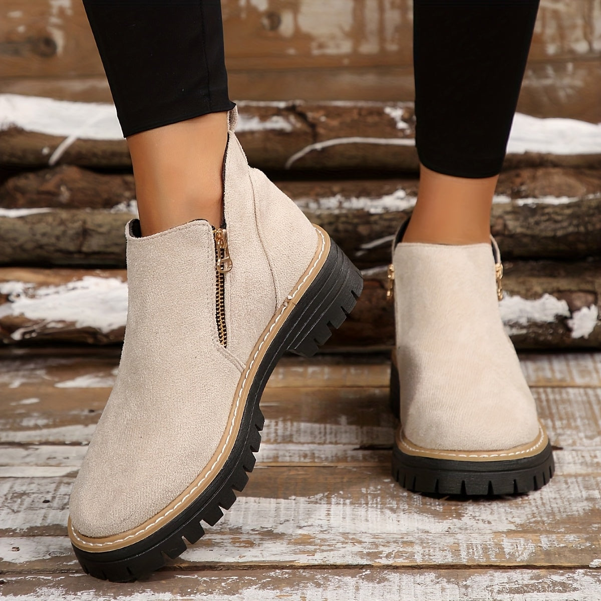 Cream ankle boots worn with black leggings, highlighting the ankle silhouette, side zips, and contrast sole stitching.