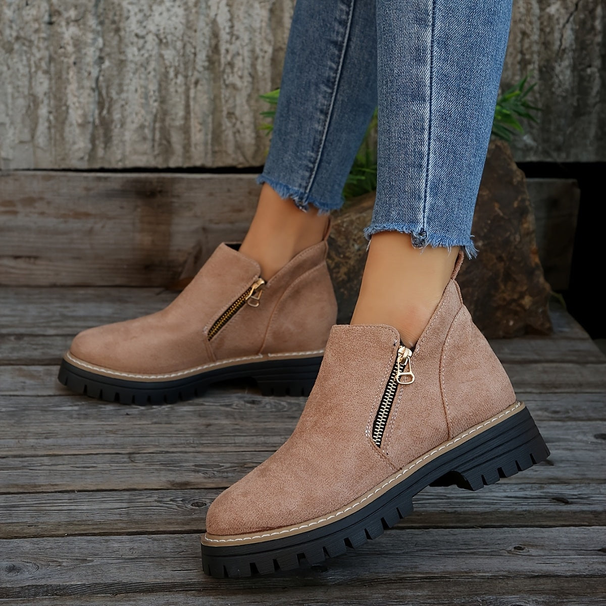 Blush ankle boots worn with cropped jeans outdoors, showing the side zips and bold lug soles.