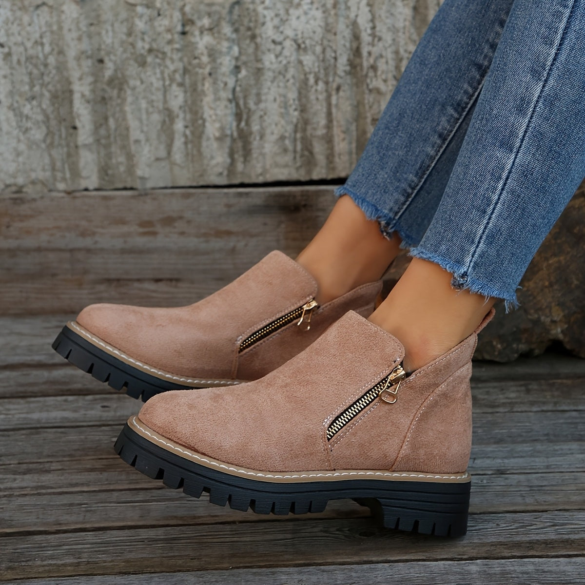 Blush ankle boots worn with cropped jeans in a close side view, showing the paired side zips and low heels.