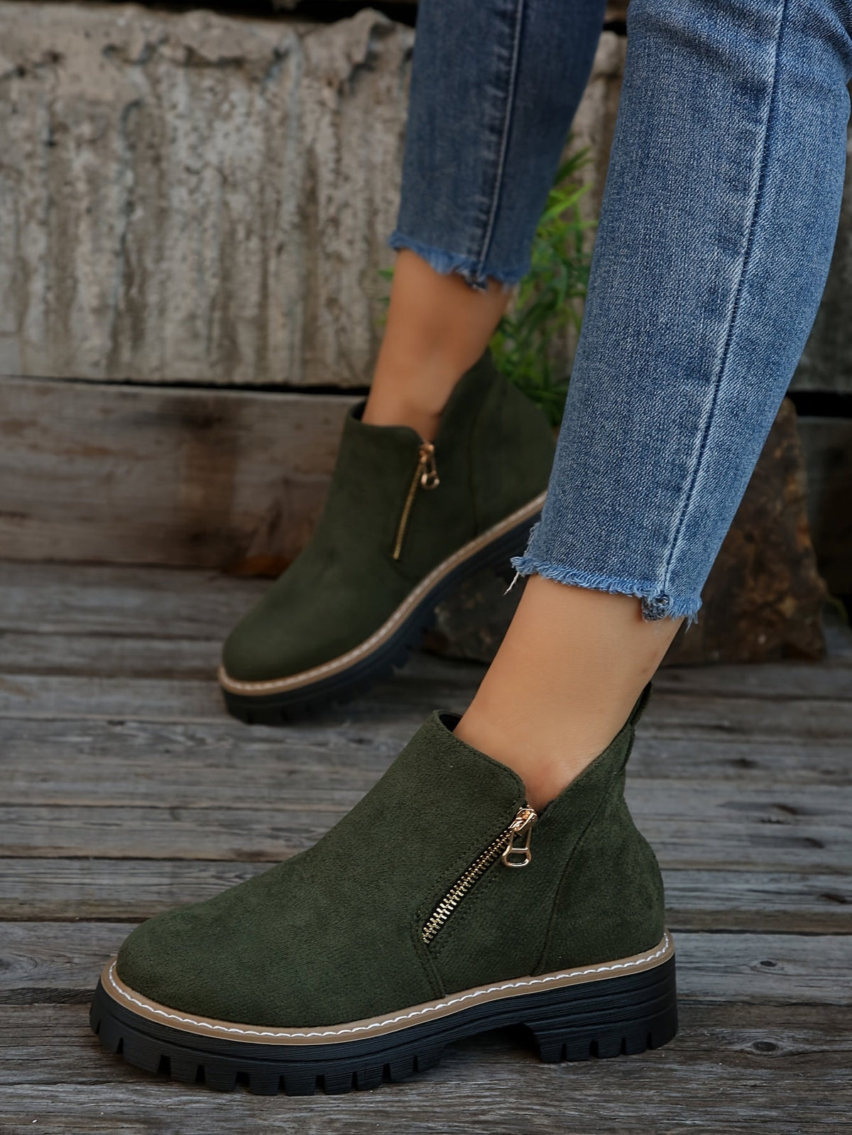 Green ankle boots worn with cropped jeans outdoors, showing the clean ankle height and lug soles.