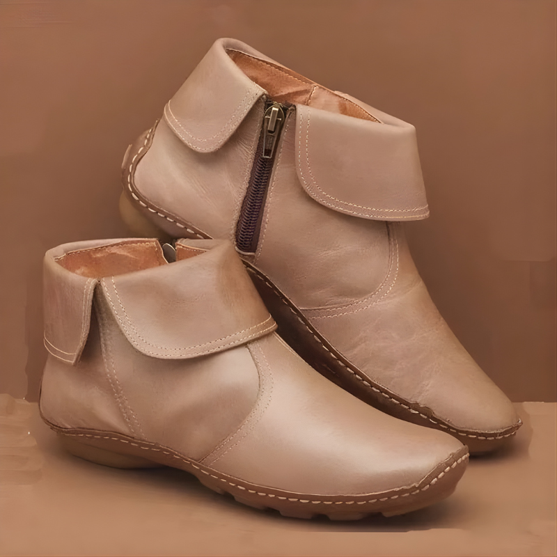 Tan ankle boots displayed with one boot resting behind the other, highlighting the wrap panels, curved toe shape, and side zipper.