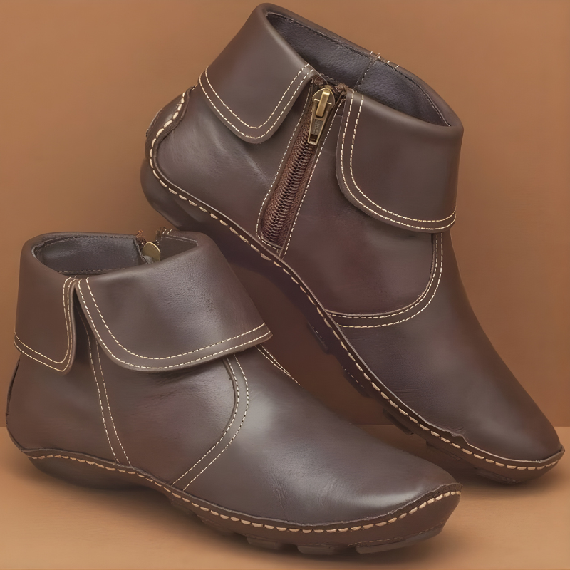 Dark brown ankle boots shown at an angled view, featuring layered wrap details, light contrast stitching, and textured soles.