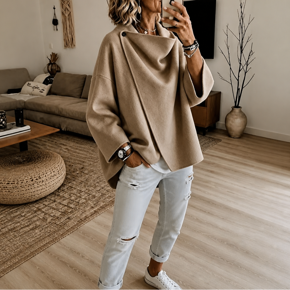 Tan version of the asymmetric wrap cape jacket showing the draped front, buttoned collar, and three-quarter sleeves.