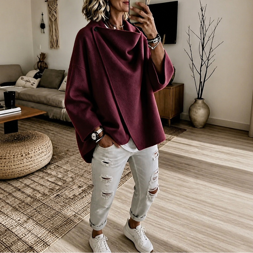 Deep burgundy version of the asymmetric wrap cape jacket showing its overlapping front and relaxed sleeve openings.