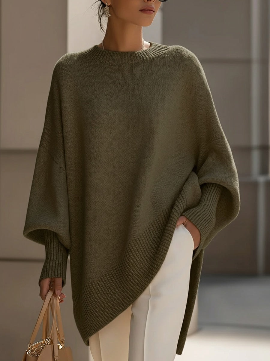 Olive asymmetric poncho sweater with a relaxed batwing silhouette, ribbed edges, and a long pointed front hem.