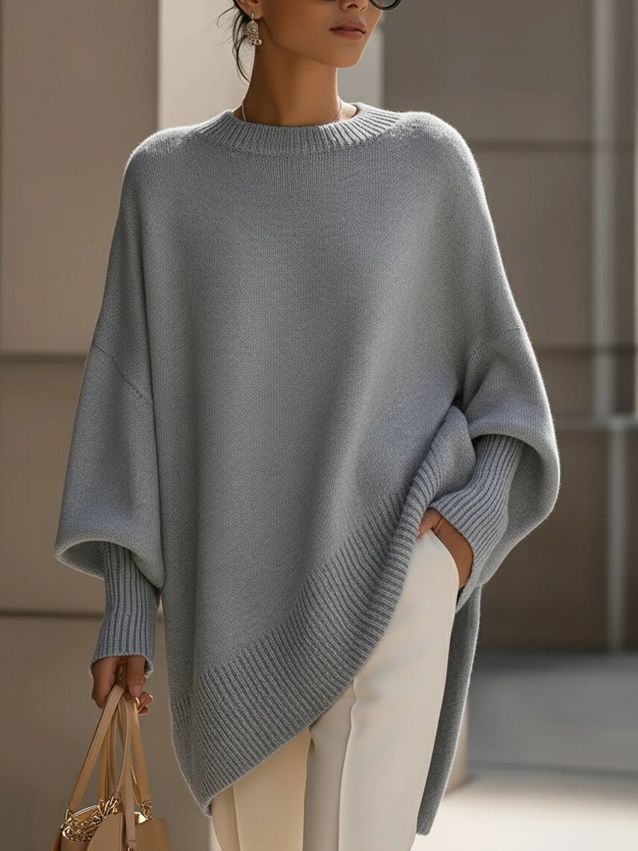 Gray asymmetric poncho sweater featuring a ribbed crew neckline, batwing sleeves, and a sweeping front hem.
