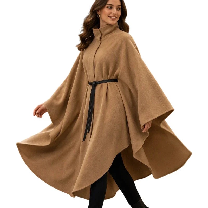 Camel cape coat on a plain background, shown in a full flowing silhouette with stand collar, black belt, and asymmetric hem.