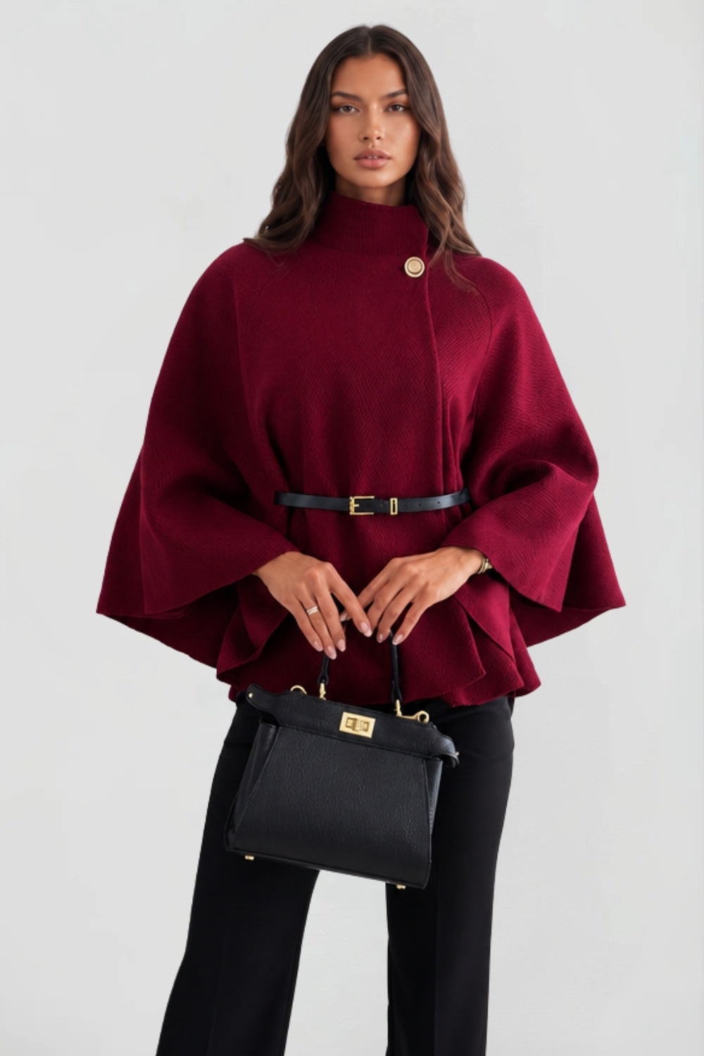 Front view of the burgundy belted cape jacket with high stand collar, statement button, and wide sleeves.