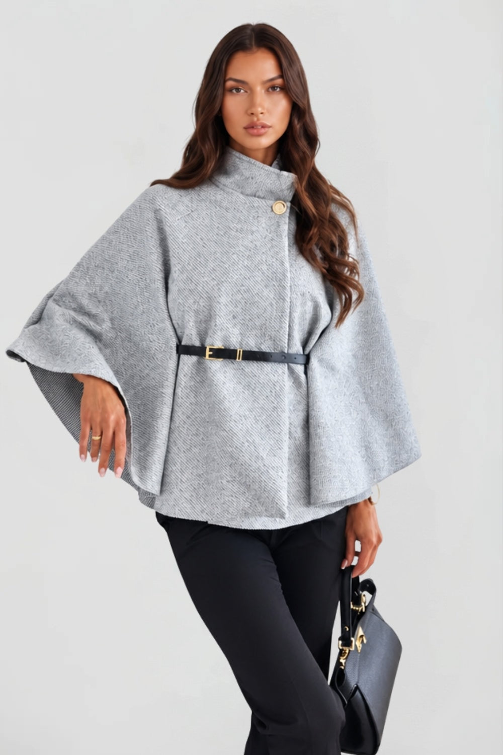 Angled front view of the light gray cape jacket with one sleeve lifted to show its wide, fluid shape.