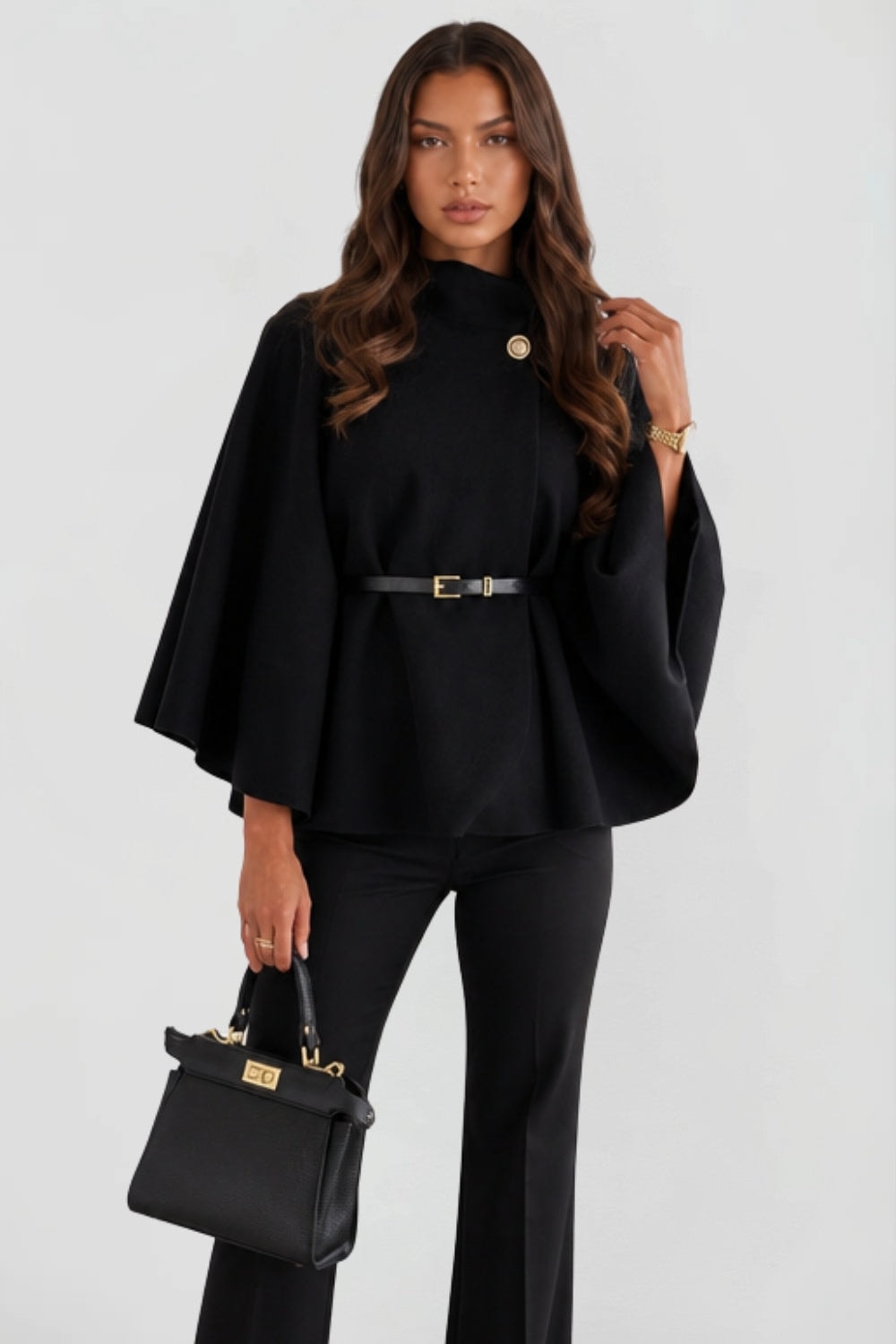 Full front view of the black belted cape jacket, showing its relaxed oversized shape over trousers.