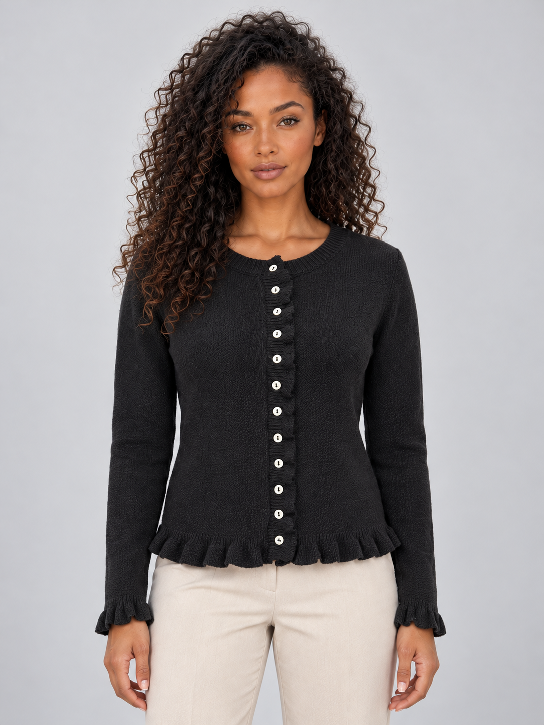 Front view of a black button-front cardigan with a round neckline, fitted long sleeves, and ruffle trim at the hem and cuffs.