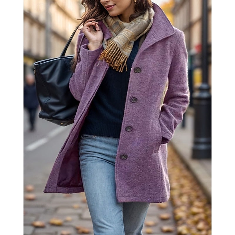 Purple mid-length button-front coat with a notched collar, long sleeves, and front pockets styled with jeans on a city street.