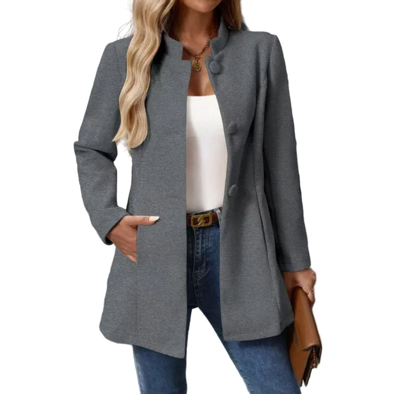 Gray button-front collarless longline coat styled open over a white top and jeans, with one hand in a side pocket.