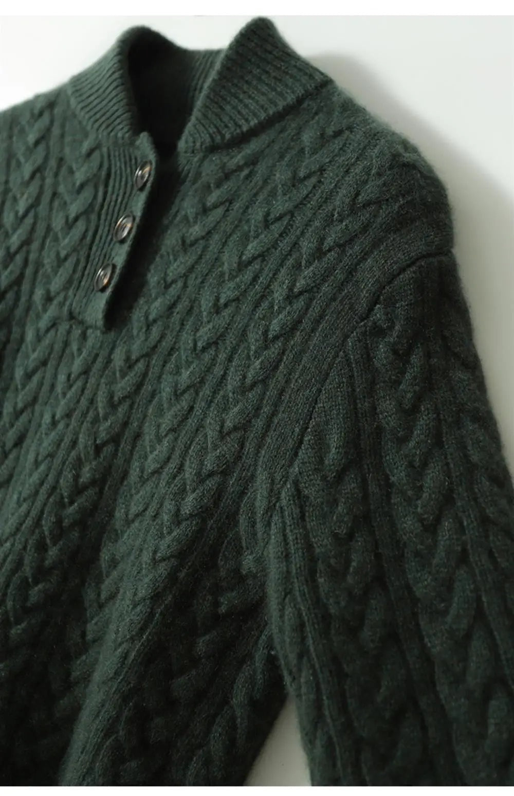 Angled detail of the dark green sweater showing the cable knit shoulder, sleeve, and button placket.