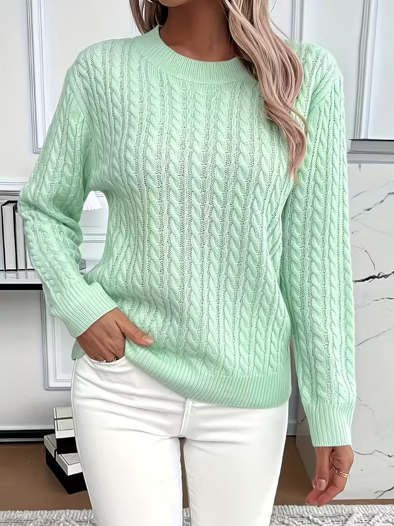 Mint green cable knit sweater with a ribbed crew neckline and cuffs, shown front-facing with one hand at the hem.