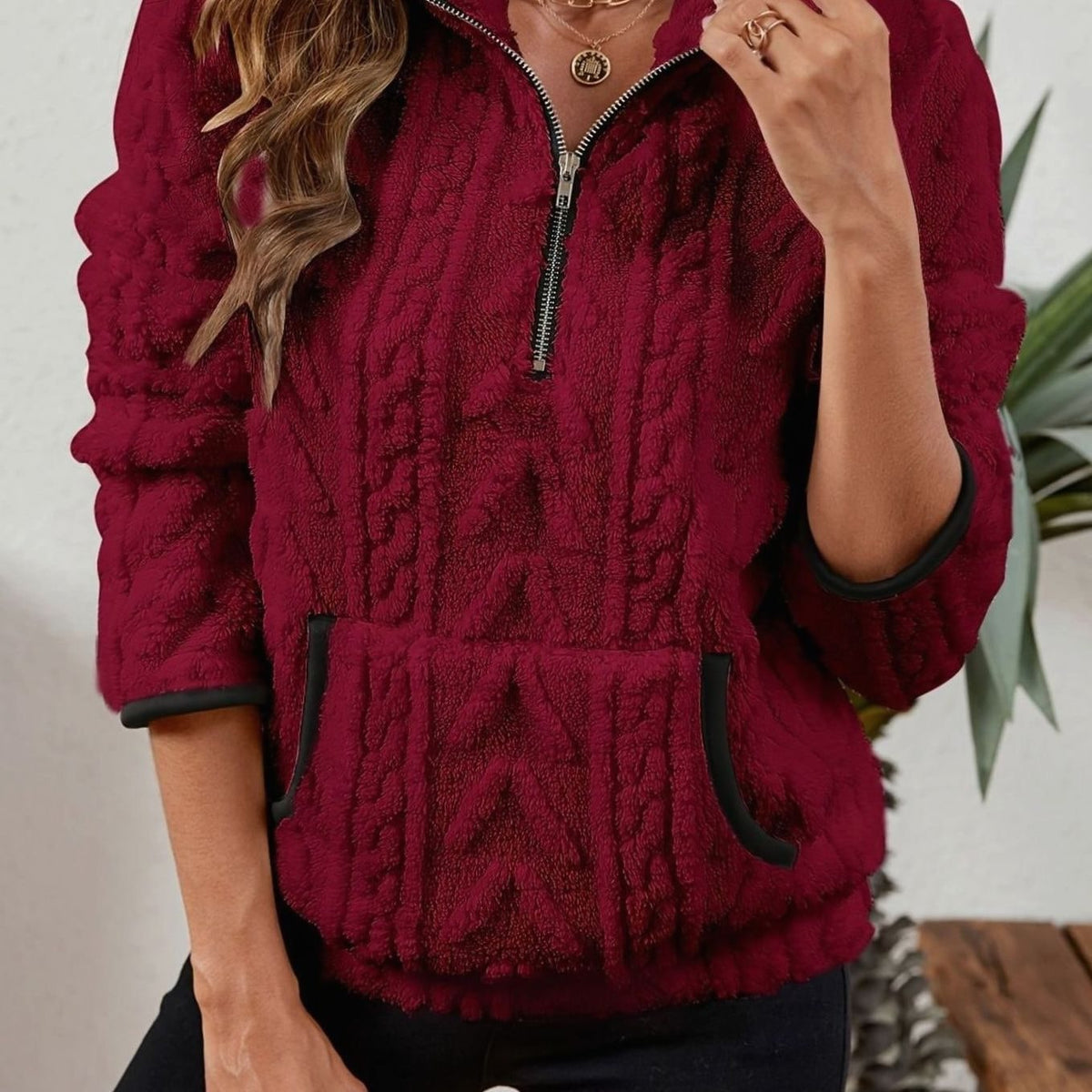 Close front view of a burgundy quarter-zip pullover with raised cable texture, stand collar, kangaroo pocket, and contrasting dark trim.