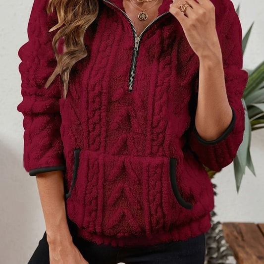 Close front view of a burgundy quarter-zip pullover with raised cable texture, stand collar, kangaroo pocket, and contrasting dark trim.