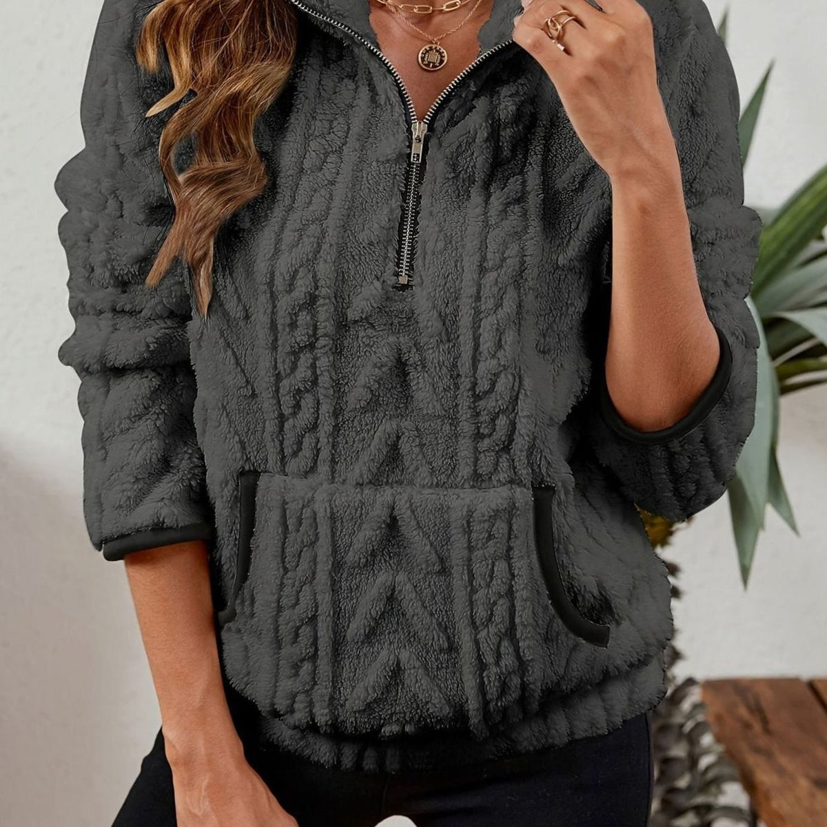 Close front view of the pullover in charcoal gray with a quarter zip, cable-textured finish, and kangaroo pocket.