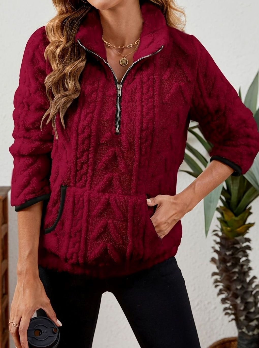 Front view of the burgundy quarter-zip pullover styled with one hand in the pocket and a takeaway cup in the other.