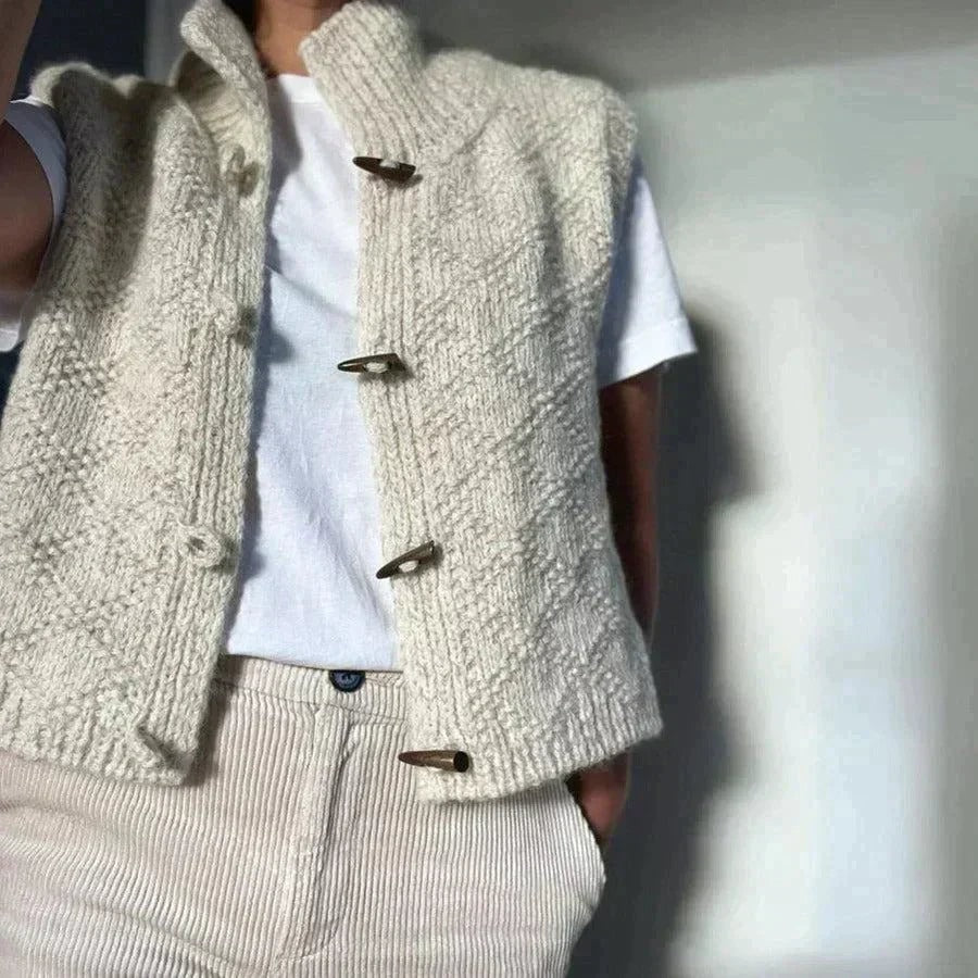 Chunky textured vest styled over a white T-shirt, showing the open armholes, high neck, and four front toggles.