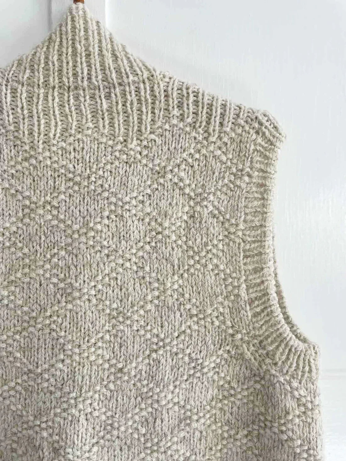 Close-up of the vest’s back shoulder and armhole, showing the textured knit body and ribbed neckline edge.