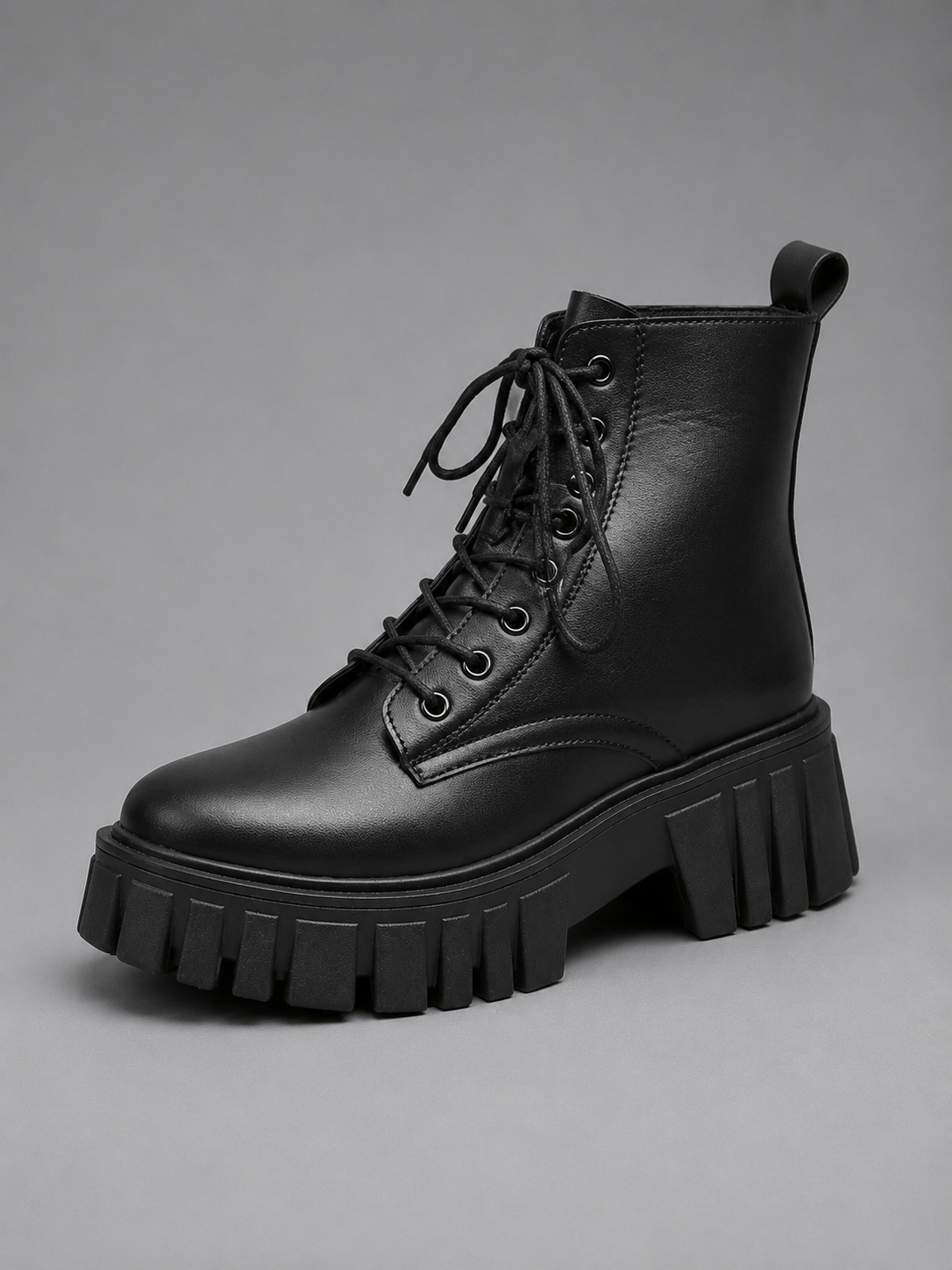Black ankle-height combat boot shown from a front three-quarter angle with chunky platform sole, rounded toe, lace-up fastening, and deep tread.
