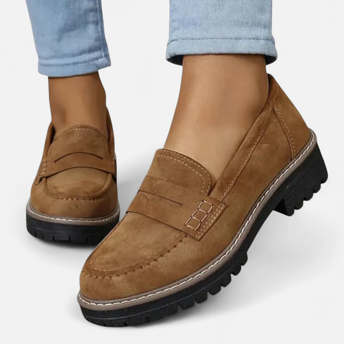 Brown penny loafers worn with light blue jeans, shown from the front and side to emphasize the stitched toe and contrast welt.