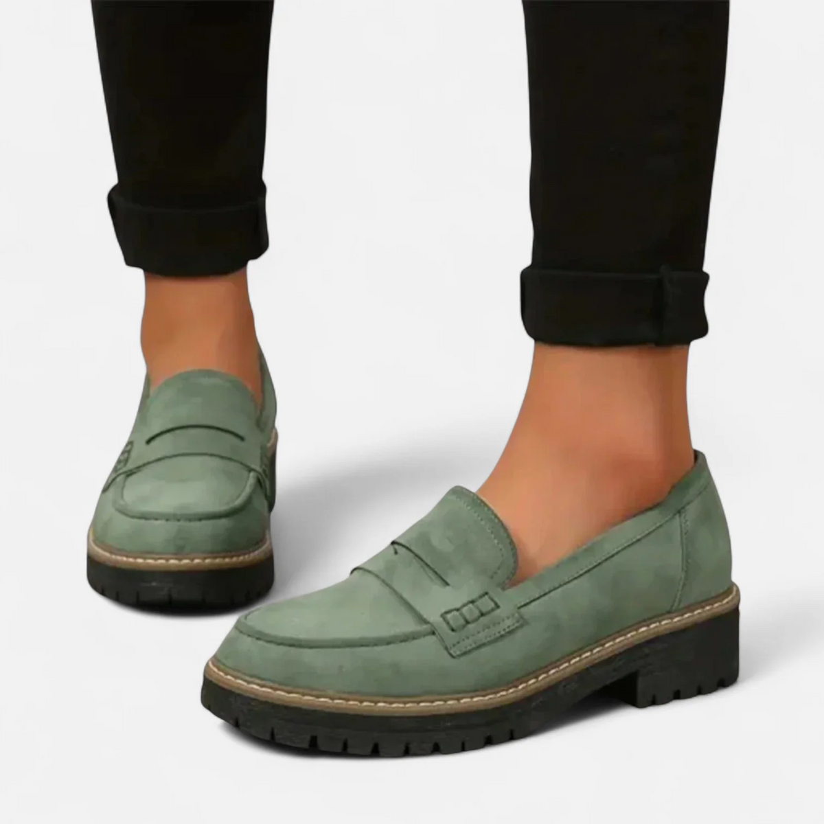 Green penny loafers worn with rolled black trousers, shown in a side profile that displays the slip-on opening and thick sole.
