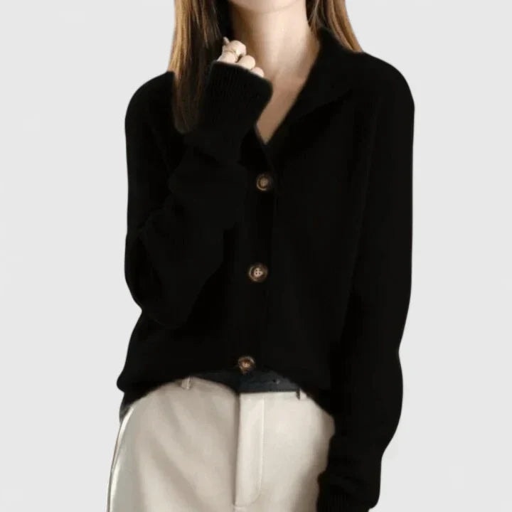 Black collared button-front cardigan paired with light trousers, shown with the front partly fastened and long sleeves.