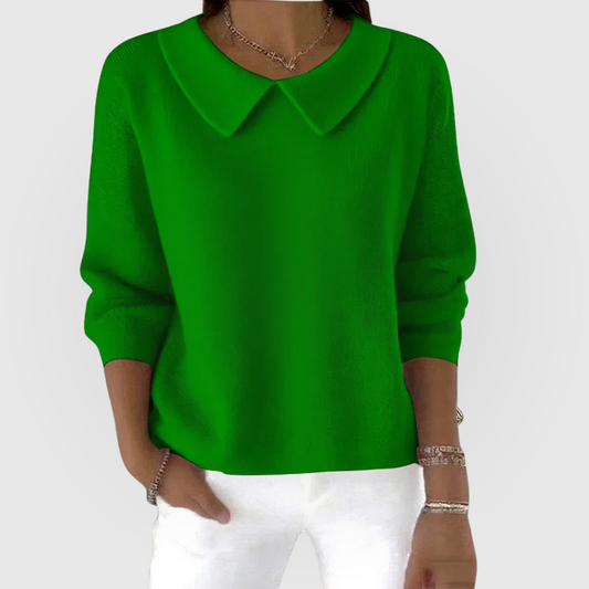 Green relaxed-fit sweater with a pointed collar, long sleeves, fitted cuffs, and a hip-length hem, styled with white trousers.