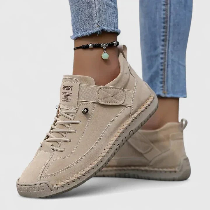 Beige low-top sneakers featuring laces, ankle straps, and textured outsoles, shown from the side.