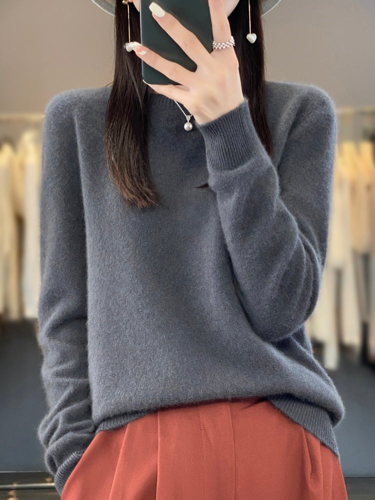 Charcoal gray crew neck sweater with long sleeves and ribbed cuffs, worn with rust-colored trousers.