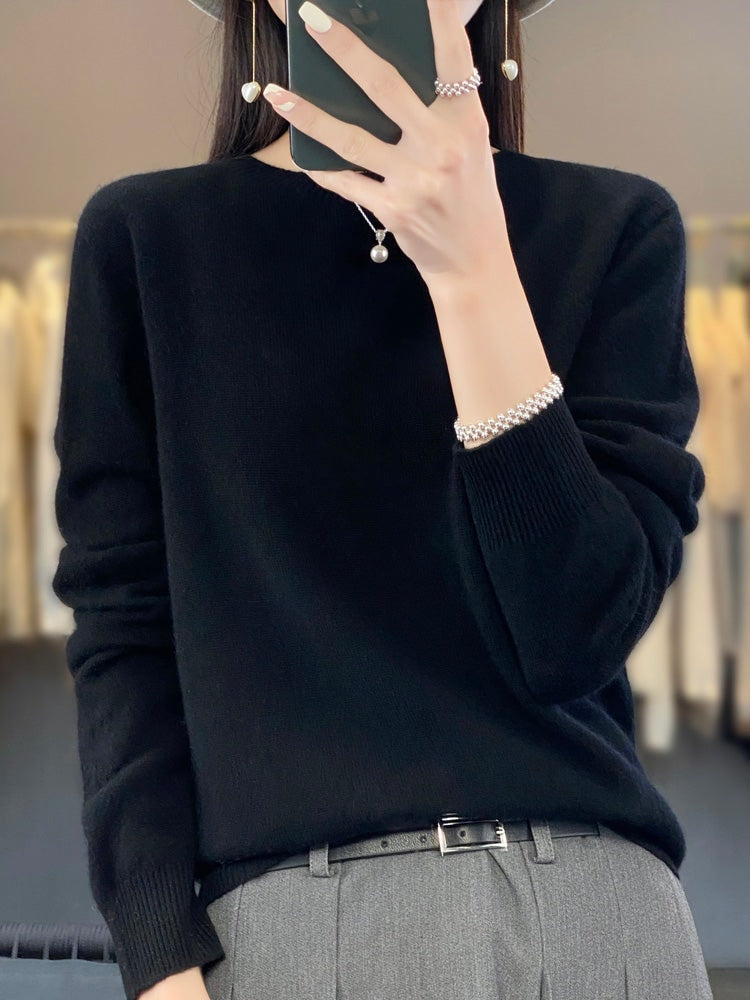 Black crew neck sweater with long sleeves and ribbed cuffs, styled with gray tailored trousers.