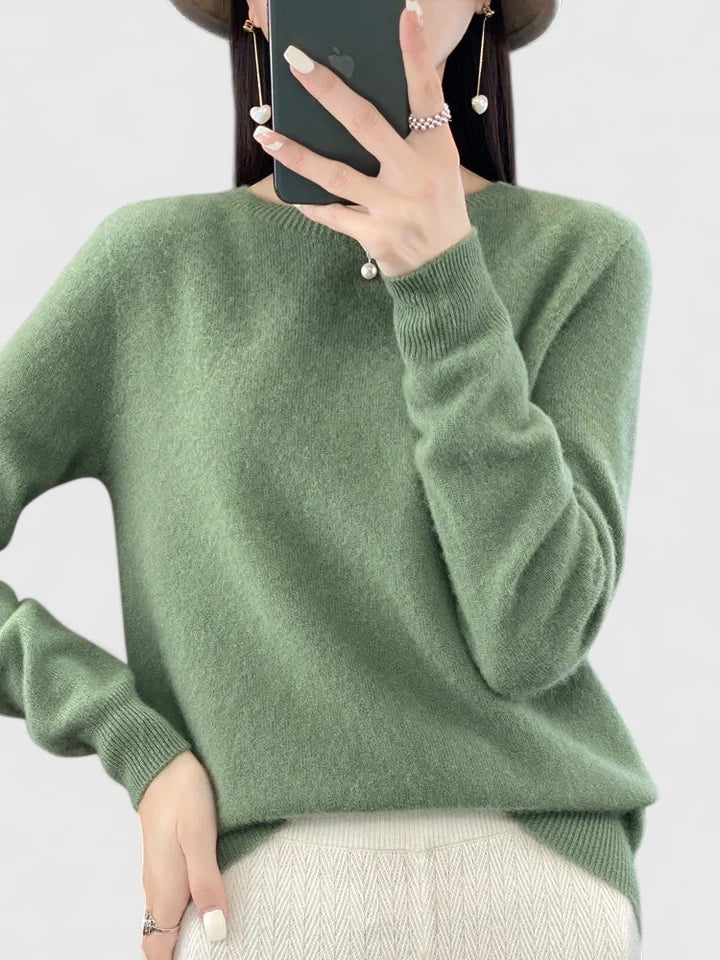 Sage green crew neck sweater against a plain background, showing its relaxed fit and ribbed sleeve cuffs.