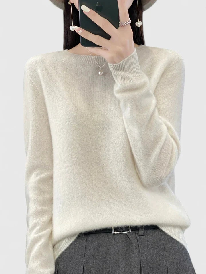 Ivory crew neck sweater against a plain background, styled with dark tailored trousers and a visible belt.