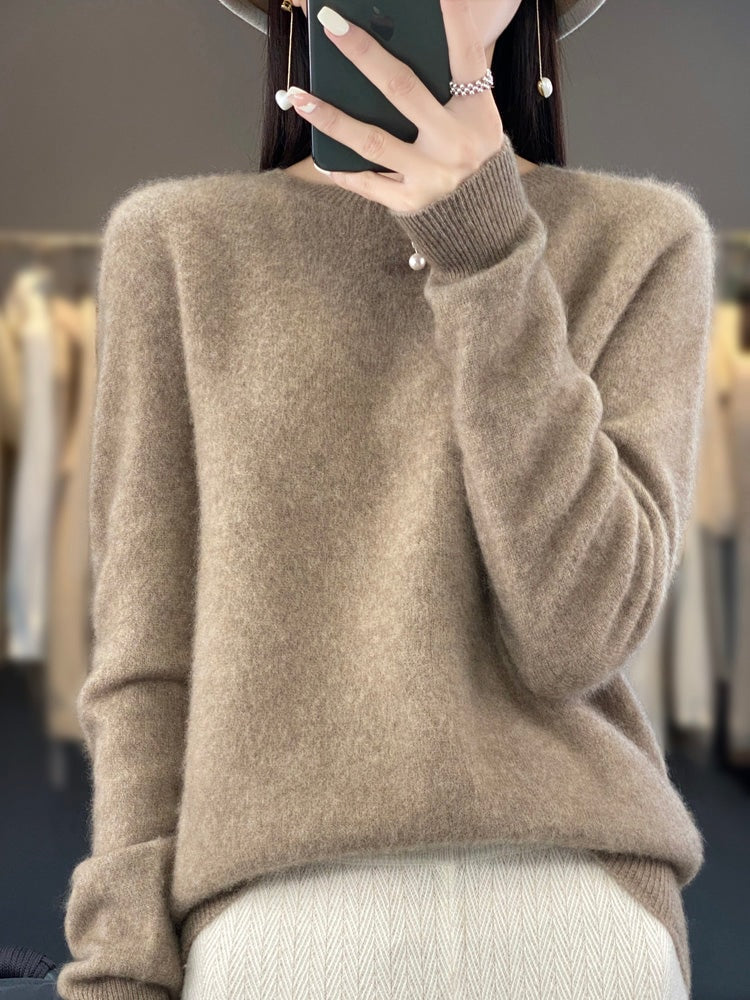Taupe crew neck sweater with long sleeves, ribbed cuffs, and a gently loose hem over light trousers.