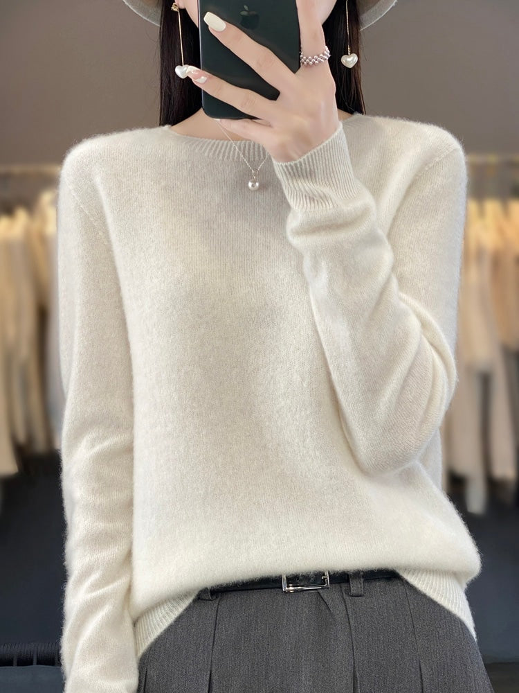 Ivory crew neck sweater with long sleeves and ribbed cuffs, paired with dark trousers.