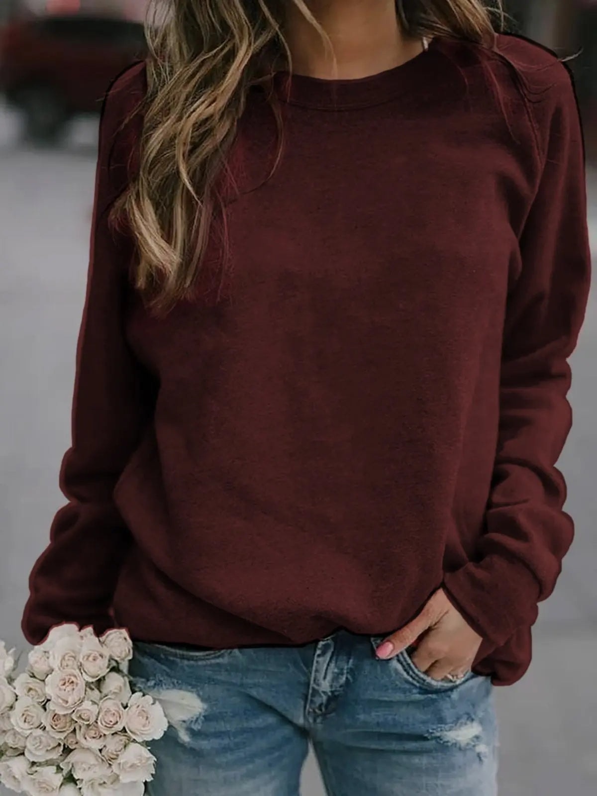 Burgundy women's crew neck sweatshirt with long raglan sleeves, ribbed cuffs, and ribbed hem, styled with jeans.