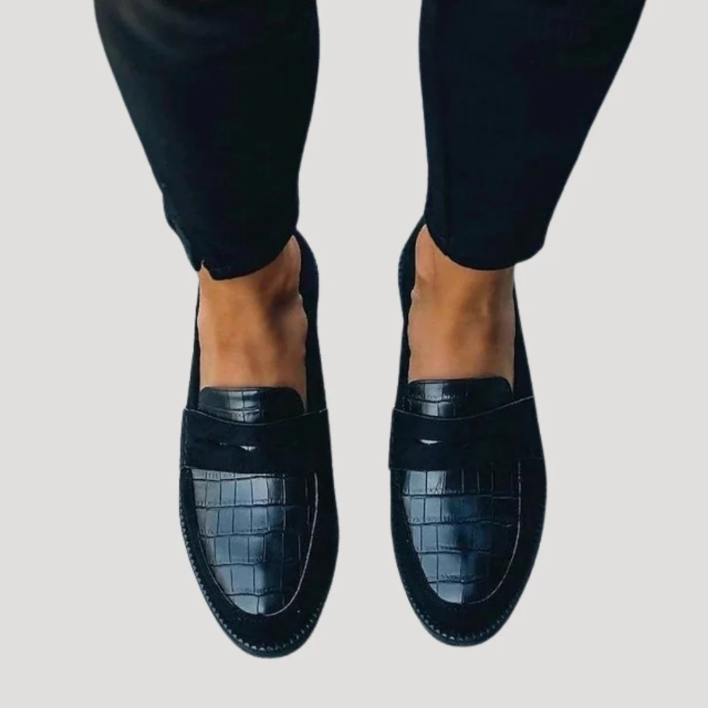 Front-facing view of black slip-on penny loafers with rounded almond toes, horizontal penny straps, and croc-embossed vamp panels.