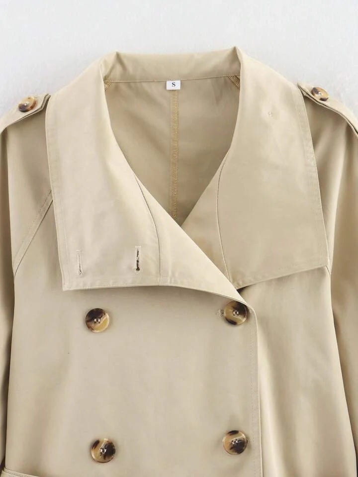 Close-up of the beige trench coat upper front showing the wide collar, double-breasted buttons, and shoulder epaulettes.