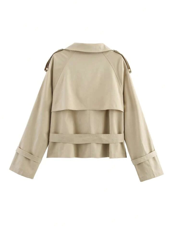 Back view of the beige cropped trench coat showing the shoulder epaulettes, back storm flap, waist band, and cuff straps.