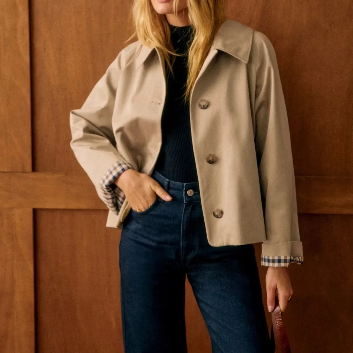 Beige cropped jacket paired with high-waisted dark jeans, with one hand resting in a pocket.