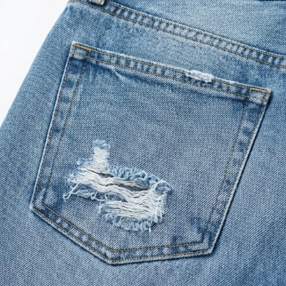 Close-up of a back pocket featuring contrast stitching and a prominent distressed tear.