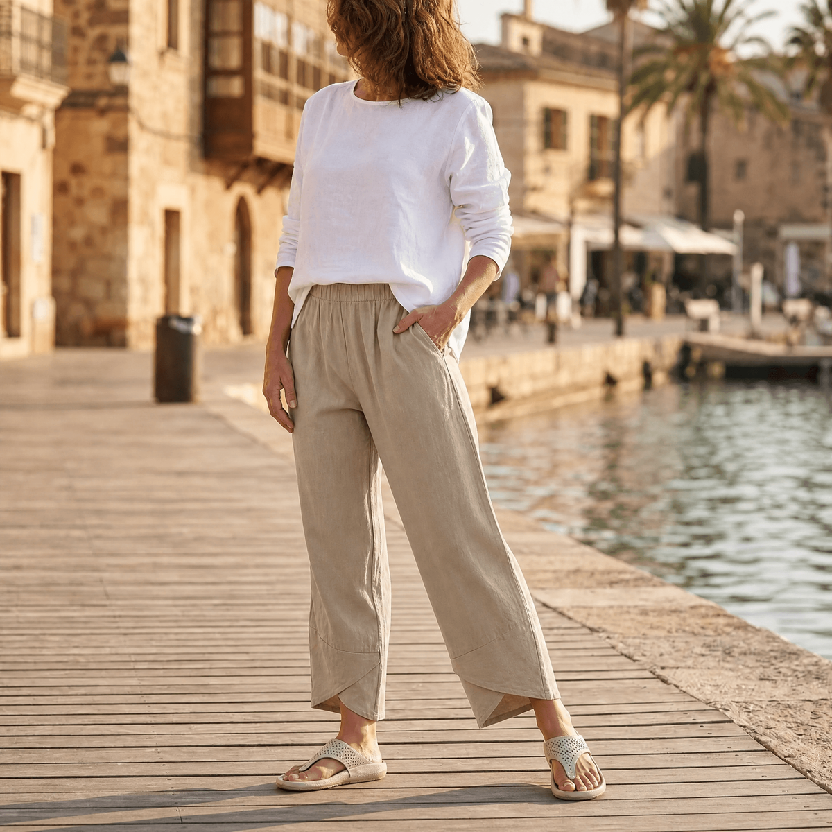Front view of beige cropped wide-leg pants showing the elastic waist, side pocket, and pointed crossover hems.