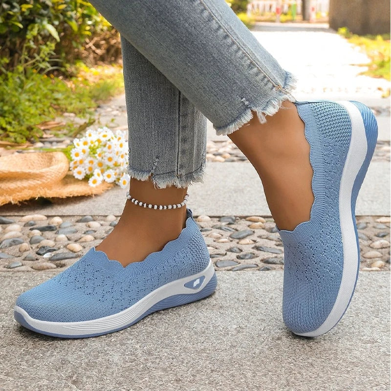 Blue knit slip-on shoes displayed in a split stance with one shoe raised and the cushioned sole visible.