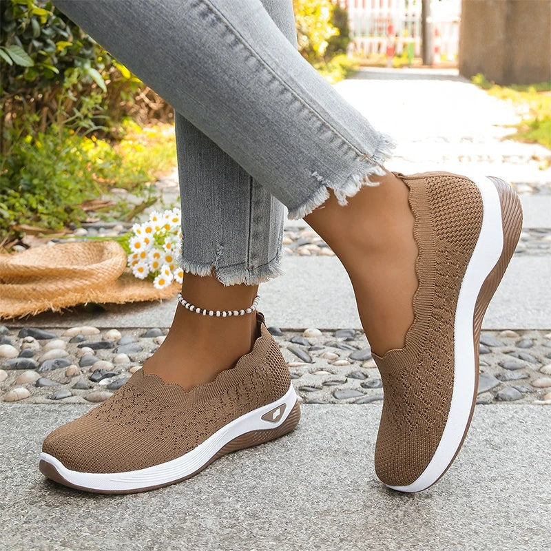Brown knit slip-on shoes shown with one shoe lifted, revealing the white midsole and textured outsole.