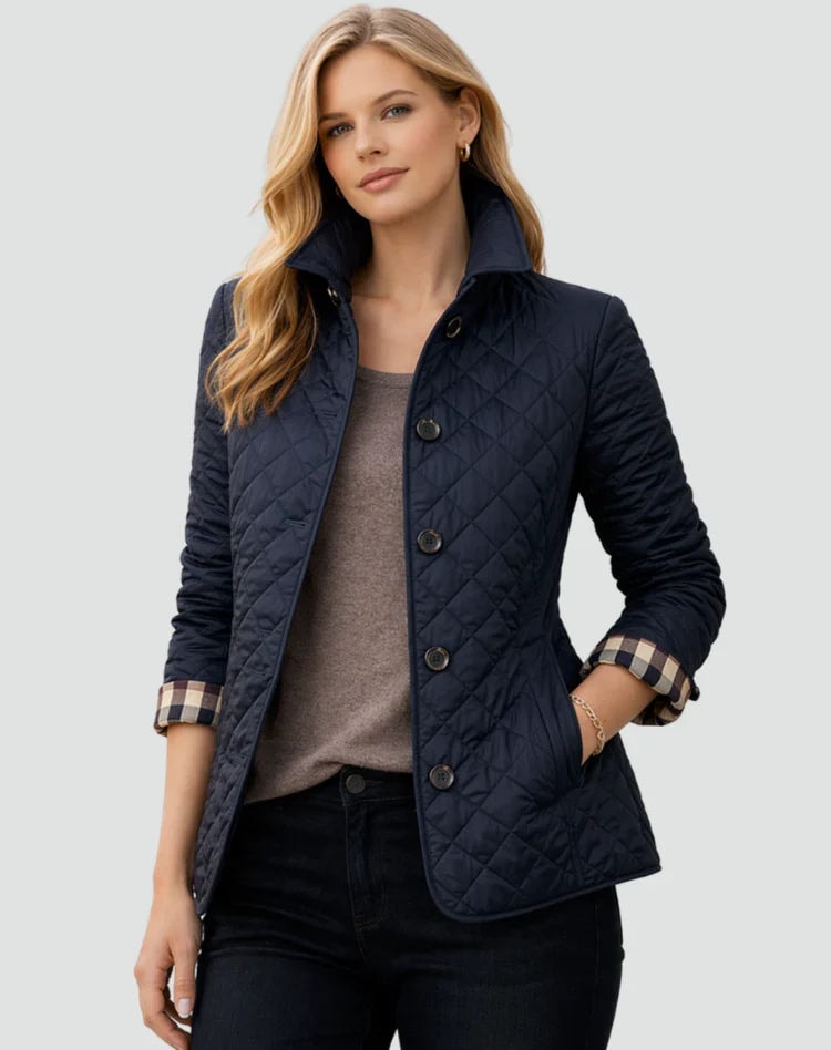 Deep navy diamond-quilted jacket with an upright collar, button-front closure, long sleeves, and side pockets, paired with a brown top.